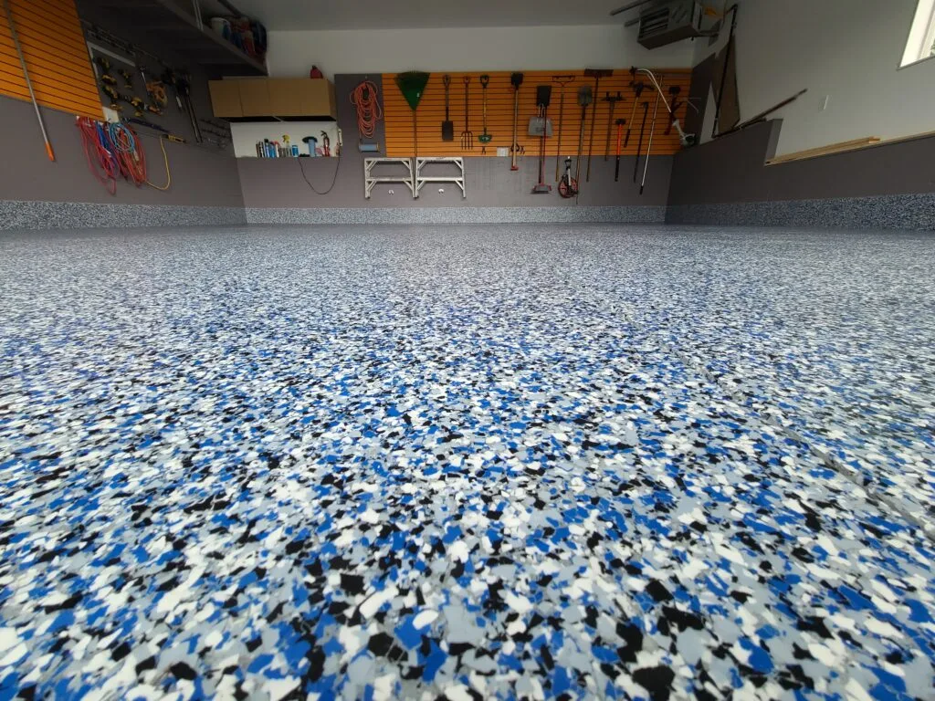 Epoxy flake broadcast garage floor coating installed in Calgary with a seamless cove base. Durable, UV-stable, and resistant to chemicals, abrasion, and hot tire pickup.